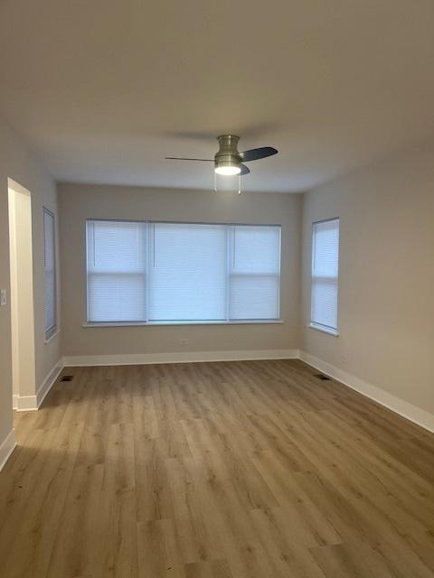 unfurnished room with wood finished floors, a ceiling fan, and baseboards