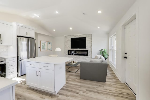 kitchen with open floor plan, appliances with stainless steel finishes, white cabinets, light countertops, and lofted ceiling