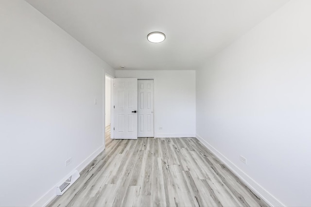 spare room featuring light wood-style floors, visible vents, and baseboards