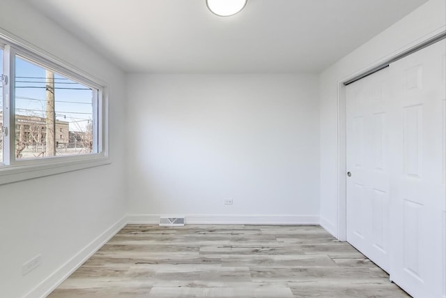 unfurnished bedroom with a closet, visible vents, light wood-style floors, and baseboards