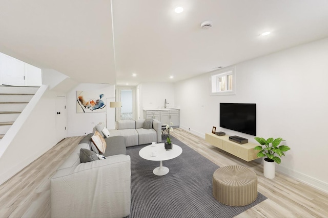 living room featuring recessed lighting, light wood-type flooring, baseboards, and stairway