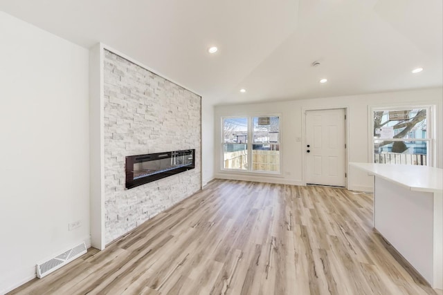 unfurnished living room featuring recessed lighting, visible vents, light wood-style floors, and a stone fireplace