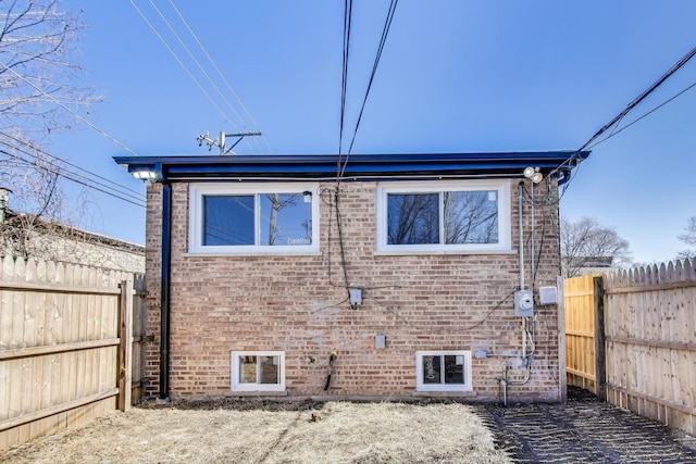 view of property exterior with brick siding and a fenced backyard