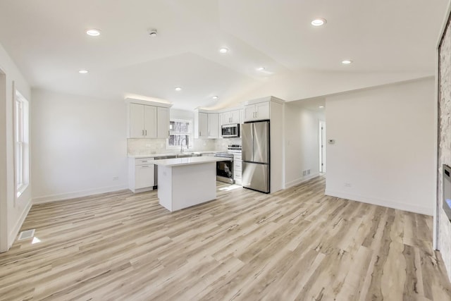 kitchen featuring a sink, tasteful backsplash, stainless steel appliances, light countertops, and vaulted ceiling