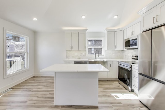 kitchen featuring visible vents, a sink, plenty of natural light, backsplash, and appliances with stainless steel finishes