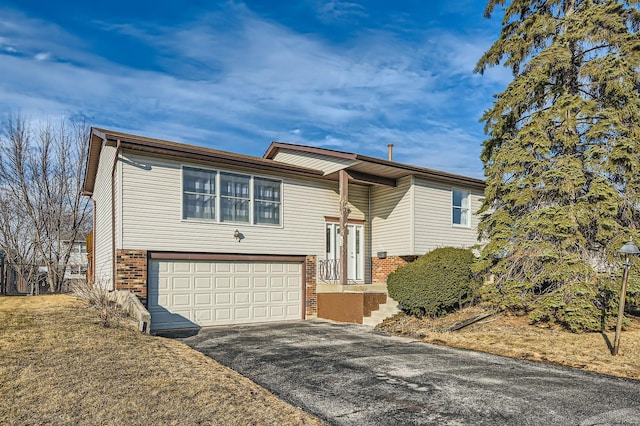 raised ranch with a garage, brick siding, and driveway