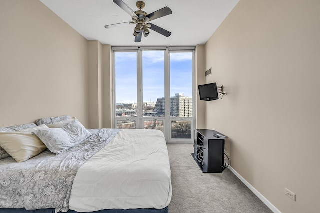 carpeted bedroom with expansive windows, baseboards, and ceiling fan