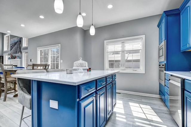 kitchen featuring blue cabinetry, light countertops, a kitchen bar, recessed lighting, and appliances with stainless steel finishes