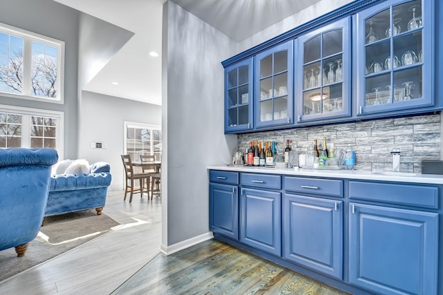 bar featuring dark wood finished floors, recessed lighting, baseboards, decorative backsplash, and bar area