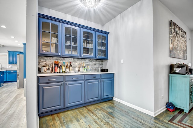 bar featuring light wood-style floors, baseboards, and tasteful backsplash