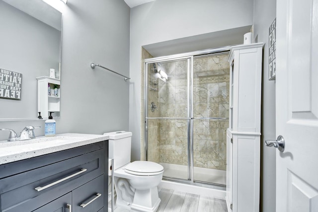 full bath with vanity, toilet, wood finished floors, and a shower stall