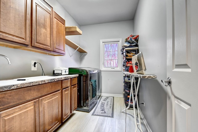 laundry area with light wood-type flooring, cabinet space, baseboards, and washer and clothes dryer