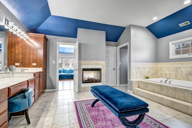 full bathroom featuring a tiled fireplace, vaulted ceiling, visible vents, and tile patterned floors