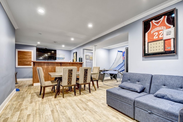 dining room featuring light wood finished floors, decorative columns, baseboards, and ornamental molding