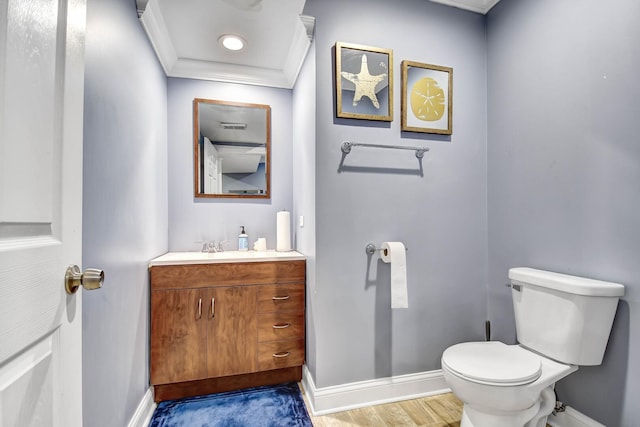 half bath with crown molding, baseboards, toilet, wood finished floors, and vanity