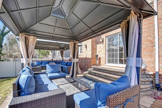 view of patio featuring a gazebo, an outdoor hangout area, entry steps, and fence