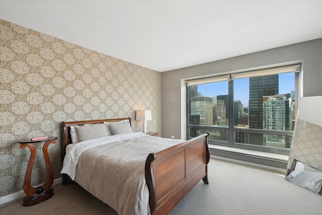 bedroom featuring a view of city, wallpapered walls, and carpet floors