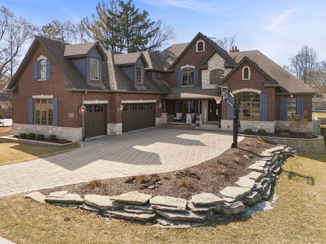 view of front of home with brick siding, a shingled roof, decorative driveway, a garage, and stone siding