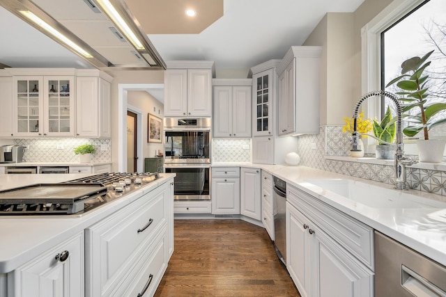 kitchen with a sink, dark wood-style floors, stainless steel appliances, white cabinets, and light countertops