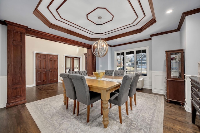 dining space with a tray ceiling, an inviting chandelier, dark wood-style floors, and wainscoting