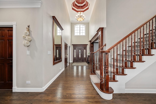 foyer entrance with a notable chandelier, wood finished floors, baseboards, and a towering ceiling