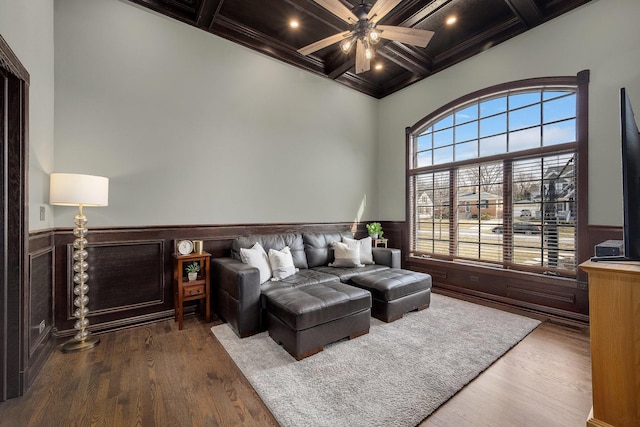 bedroom featuring beam ceiling, coffered ceiling, wood finished floors, and wainscoting