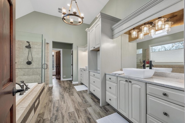 bathroom with a shower stall, vanity, lofted ceiling, and wood finished floors