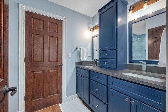 full bathroom featuring double vanity, wood finished floors, baseboards, and a sink