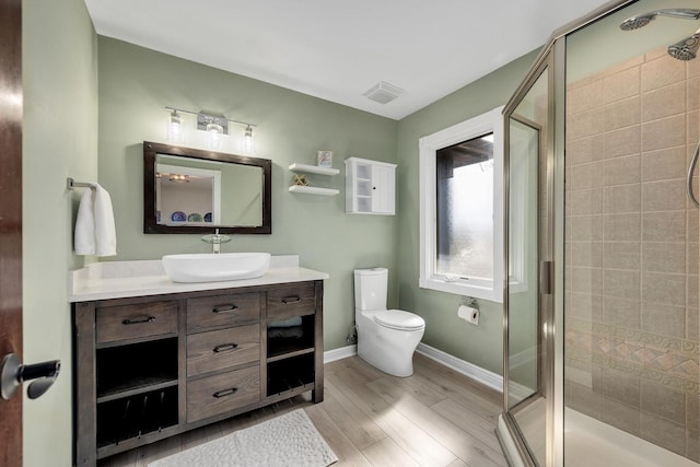 bathroom featuring visible vents, toilet, a stall shower, wood finished floors, and vanity