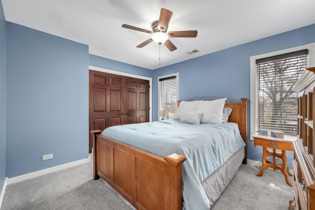 bedroom with visible vents, baseboards, ceiling fan, a closet, and light colored carpet