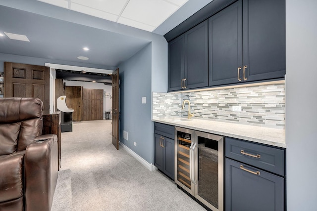 kitchen featuring tasteful backsplash, light colored carpet, beverage cooler, and blue cabinets