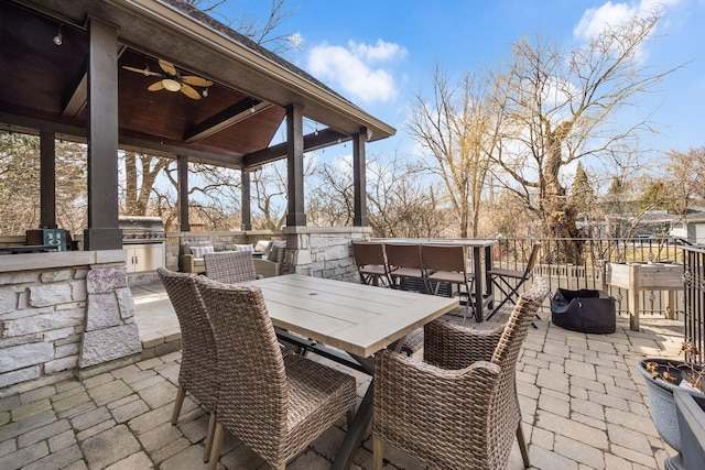 view of patio / terrace with exterior kitchen, outdoor dining area, a ceiling fan, and a grill