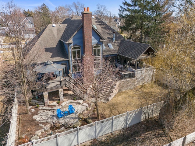 exterior space featuring a patio, a wooden deck, a fenced backyard, a chimney, and a shingled roof