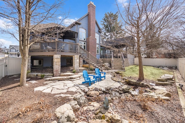 rear view of property with a deck, a patio, a fenced backyard, stairs, and a chimney