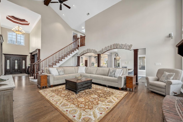 living area featuring stairway, wood finished floors, arched walkways, and ornate columns