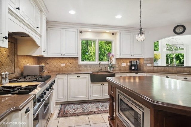 kitchen featuring a sink, tasteful backsplash, white cabinetry, stainless steel appliances, and light tile patterned flooring