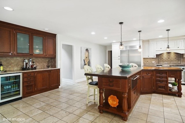 kitchen with beverage cooler, a breakfast bar, stainless steel built in fridge, decorative backsplash, and a warming drawer