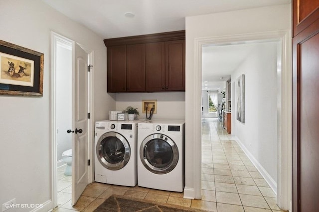 clothes washing area featuring cabinet space, light tile patterned floors, separate washer and dryer, and baseboards