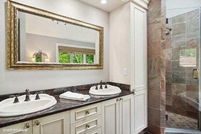 bathroom featuring double vanity, a stall shower, and a sink