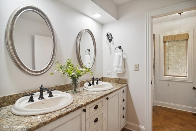 full bath featuring double vanity, baseboards, and a sink