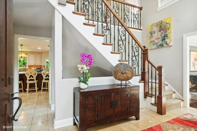 stairway with tile patterned floors, baseboards, and a towering ceiling