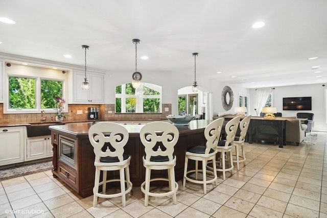 kitchen featuring a sink, stainless steel microwave, plenty of natural light, and tasteful backsplash