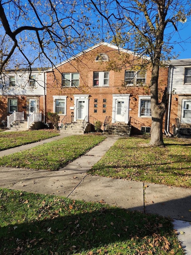 townhome / multi-family property featuring brick siding and a front lawn