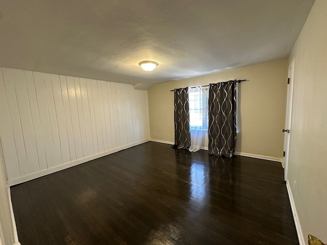 empty room with dark wood finished floors and baseboards