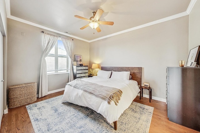 bedroom with visible vents, baseboards, light wood-style floors, and ornamental molding
