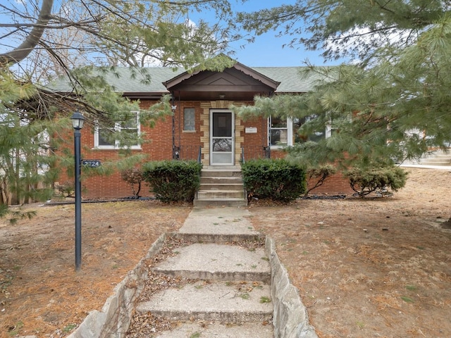 bungalow-style house featuring brick siding and roof with shingles