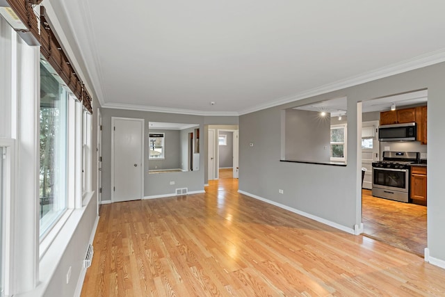 unfurnished living room with light wood finished floors, visible vents, a wealth of natural light, and ornamental molding