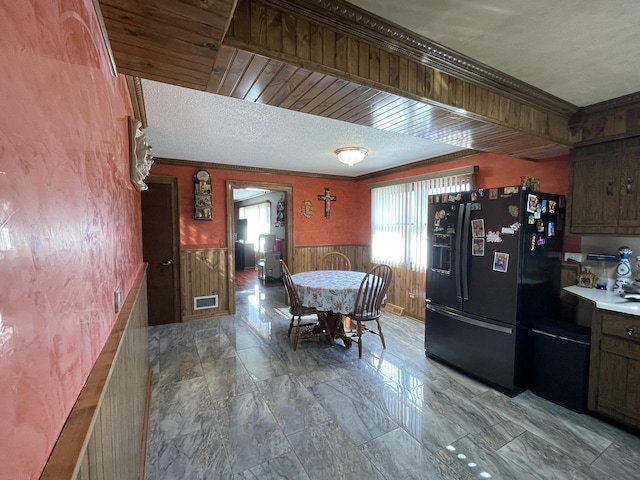 kitchen with visible vents, ornamental molding, a textured ceiling, wainscoting, and black refrigerator with ice dispenser