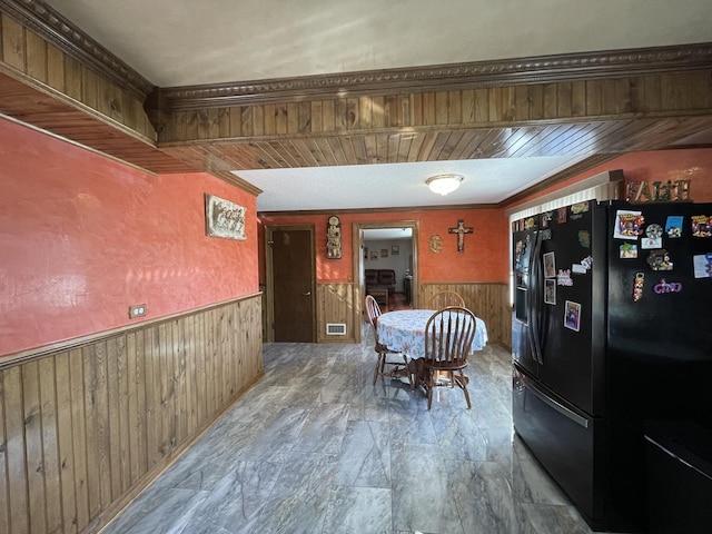 dining room with a wainscoted wall, wood walls, and visible vents