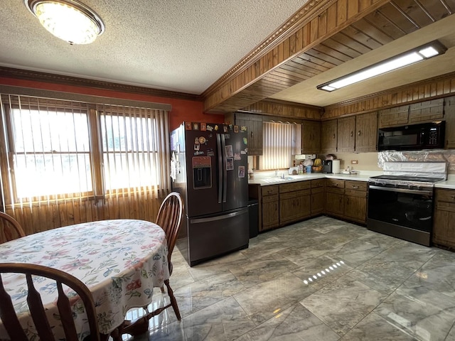 kitchen with a textured ceiling, black appliances, crown molding, and light countertops